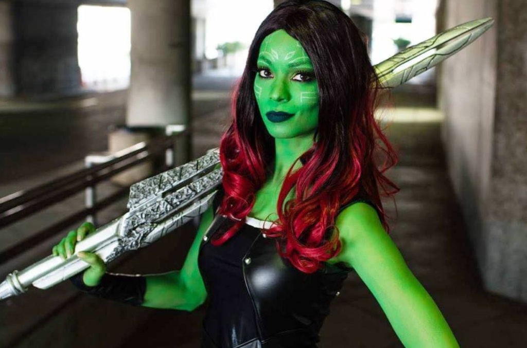 cosplay gamora avec maquillage vert, armes et cheveux rouges