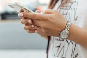 femme tenant un smartphone blanc avec montre argentée au poignet