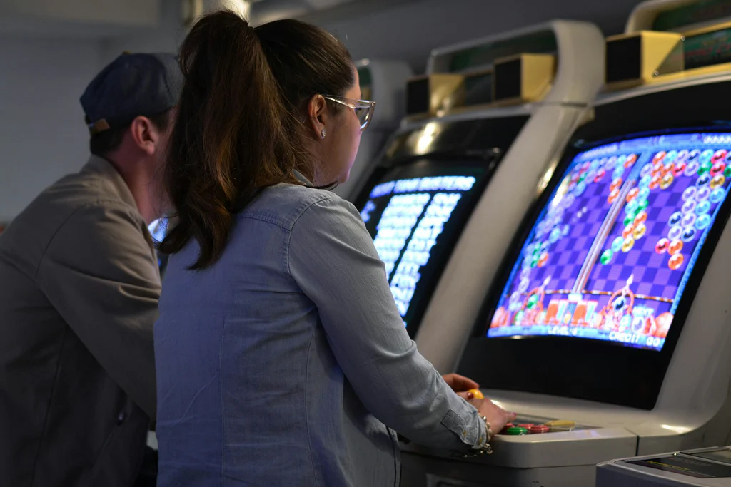 femme jouant à un jeu vidéo rétro sur borne arcade colorée