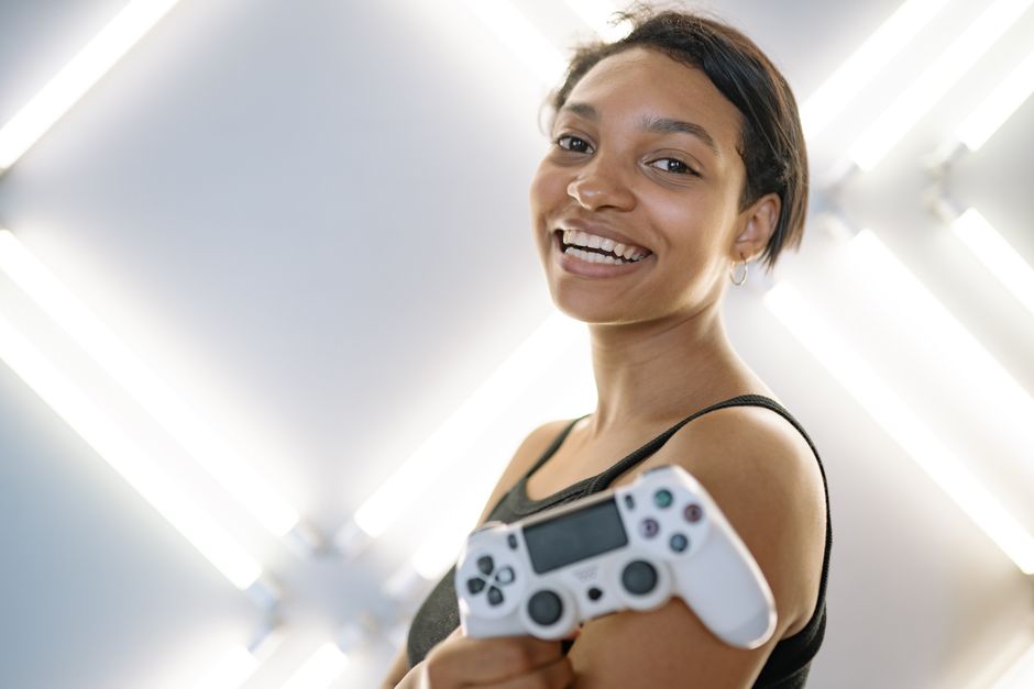 Joyful woman holding a game controller in a modern indoor setting.